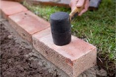 a person using a hammer to put bricks in the ground