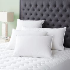 a bed with white pillows on top of it and a black headboard in the background