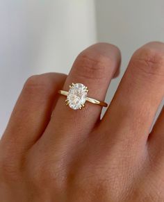 a woman's hand with a diamond ring on top of her finger, showing the center stone