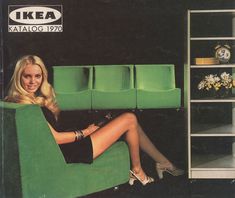 a woman sitting in a green chair next to a shelf with flowers and vases