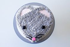 a cake decorated to look like a mouse is on a white table with gray and pink icing