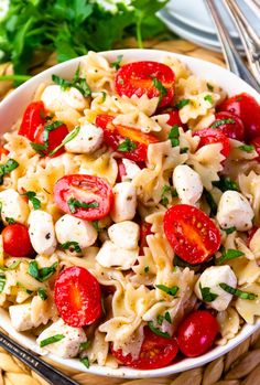 a pasta salad with tomatoes, mozzarella and parsley