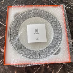 an orange and white tray with a square shaped object in it on a marble surface