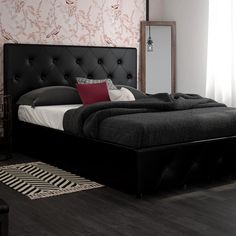 a bedroom with a black bed and red pillows on the headboard, white walls and flooring