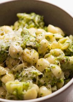 a bowl filled with pasta and broccoli covered in cheese