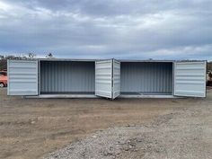 two shipping containers sitting on top of a dirt field