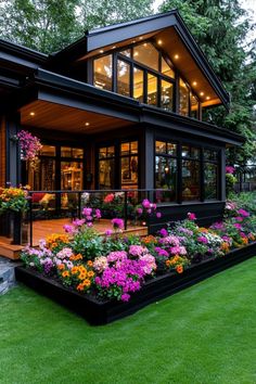 a house that has flowers in the front yard and landscaping around it, with lights on