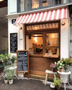 an outside view of a restaurant with flowers on the sidewalk and tables in front of it