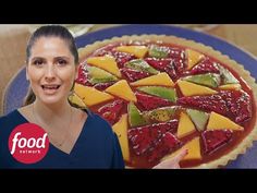 a woman standing in front of a pie with fruit toppings on it and the words food network above her