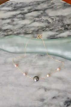 This dainty necklace is made using a 9mm Tahitian Pearl along with 4mm-5mm Edison pearls strung by a 14 karat gold filled chain. The chain is gold filled which means it does not tarnish or turn your skin green. This chain is finished with an elegant and classy 14 karat toggle clasp. Please note: The sale is for ONE necklace. All sales are final. All Violet Kalei Jewelry will arrive packaged in a gift box.  Connect with us on instagram! @violetkaleijewelry Gold Necklace With Tahitian Pearl Round Beads, Classy Necklaces, Pearl Necklace Gold, Surf Jewelry, Classy Necklace, Tahitian Pearl Necklace, Pearl Jewelry Design, Edison Pearls, Jewelry Aesthetic