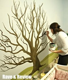 a woman painting a tree on the wall