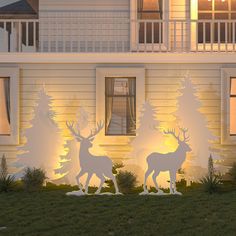 two deer statues in front of a white house with trees on the lawn at night