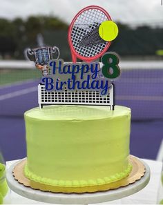 a birthday cake with a tennis racket and cupcake topper sitting on a table