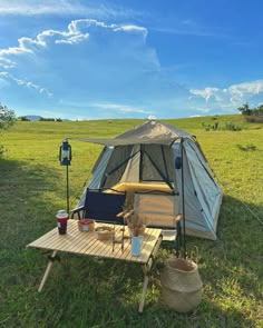 a tent is set up in the middle of a field with chairs and a table