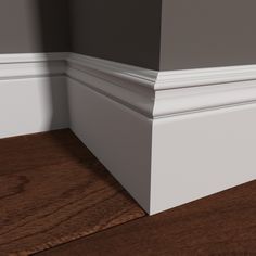 the corner of an empty room with wood flooring and white trim on it's walls