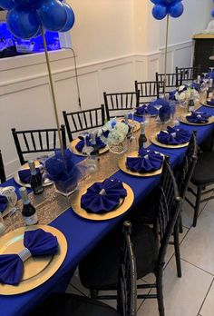 a long table set with blue and gold place settings for an elegant dinner party or celebration