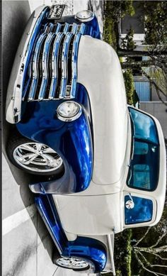 an old blue and white car parked on the side of a building