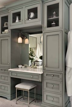 a bathroom with green cabinets and a white counter top under a large mirror on the wall