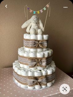 a diaper cake made to look like a baby's first birthday cake with a teddy bear on top