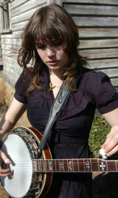 a woman is holding a small instrument in her hands and looking down at the ground