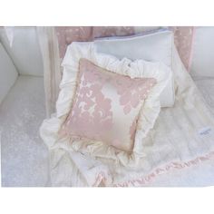 a white couch with pink and white pillows on it's back, next to a pillow case