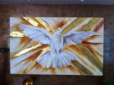 a white bird is flying in the air with its wings spread out and gold foil on it