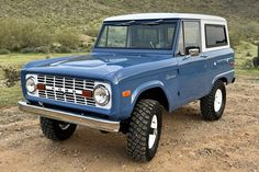 a blue truck parked on top of a dirt field