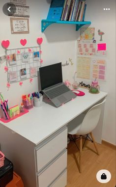 a laptop computer sitting on top of a white desk next to a shelf filled with books