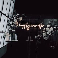 a neon sign that says happily ever after with flowers and greenery in front of it