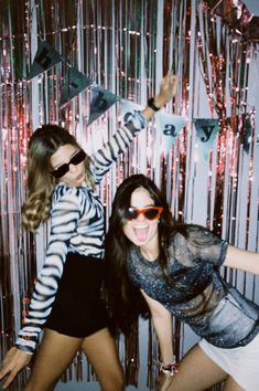 two young women posing for a photo in front of some tinsel and streamers