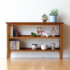 a shelf with books, cups and plants on it