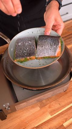 a person cooking fish in a frying pan