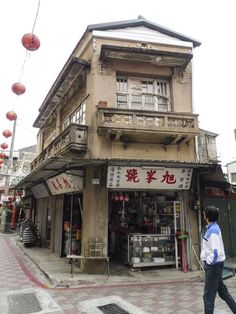 a man walking down the street in front of a building with chinese writing on it