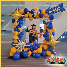 a graduation balloon arch in the shape of a star, with a graduate standing behind it