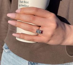 a woman's hand holding a coffee cup with a diamond ring on it,