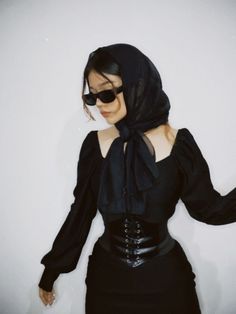 a woman in a black dress with a scarf around her neck and sunglasses on top of her head