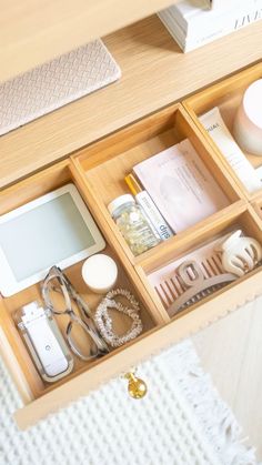 an open drawer containing various items on a bed and a table with a white blanket