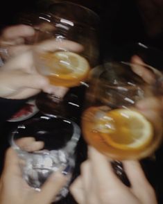 several people holding up glasses with oranges in them