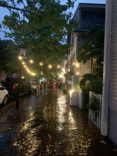 people are walking down the street in the rain at night with umbrellas and lights