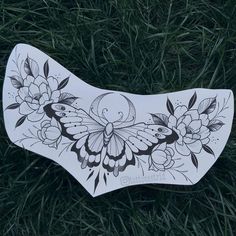 a white butterfly with flowers on it sitting in the grass