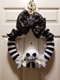 a black and white striped wreath with a stuffed panda bear hanging on the front door