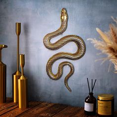 a gold snake sculpture sitting on top of a wooden table next to vases and candles