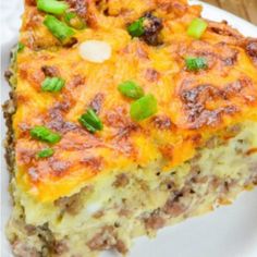 a slice of quiche on a white plate with green onions and meat toppings