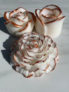 three white and gold roses sitting next to each other on top of a countertop