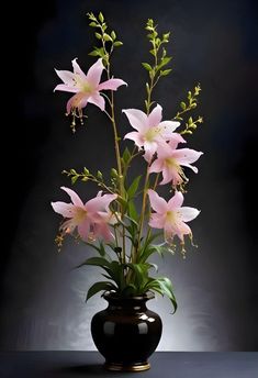 a black vase filled with pink flowers on top of a table