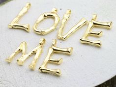 the word love me spelled in gold letters on a white surface with other words written below it