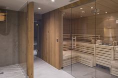 a sauna room with wooden walls and glass doors on both sides, in the middle of a bathroom