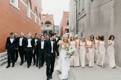 a group of people standing next to each other in front of a brick wall and building