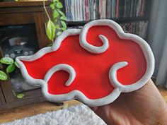 a person holding up a red and white cookie shaped like an elephant's head