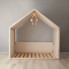 a wooden dollhouse bed with a star hanging from the ceiling